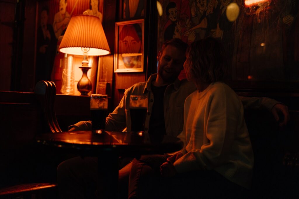 A bride and groom sit at a bar together to have a quick drink before their wedding reception.  