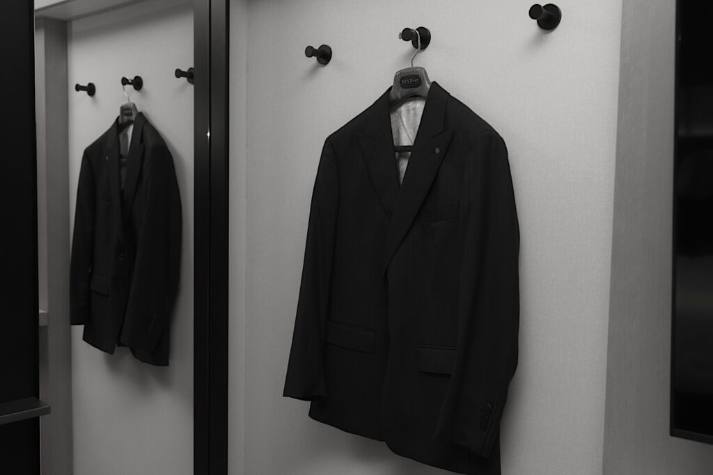 A black and white image of a grooms suit hanging on a wall in a Chicago hotel room.