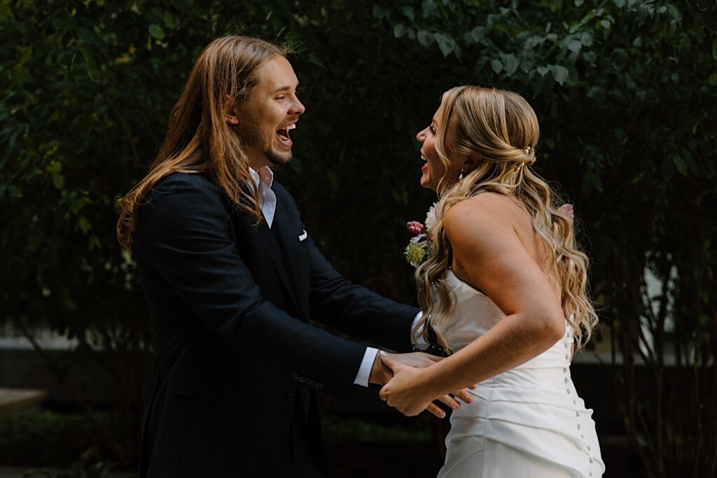 A bride and groom stand together seeing each other for the first time on their wedding morning just outside of their Chicago hotel.  The bride is wearing a romantic pleated strapless dress with buttons going down the back bodice.