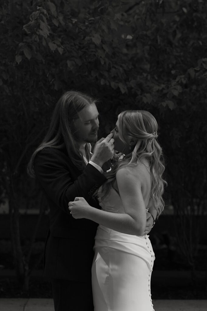 A bride and groom have a moment together the morning of their wedding outside of their Chicago hotel.  The bride wears a pleated grecian inspired strapless wedding dress.  The groom is wearing a simple black sport coat with an open button up shirt. 