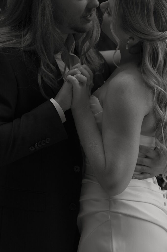 A close up documentary style image of a bride and groom holding hands and embracing the morning of their wedding just outside of their Chicago hotel room.