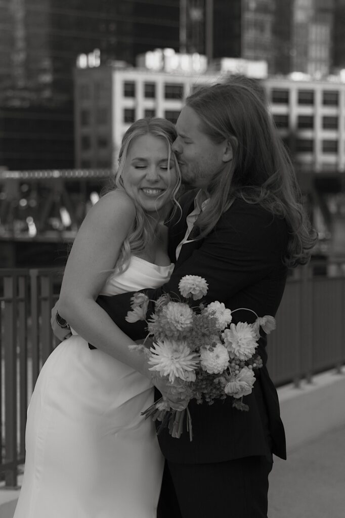 A bride and groom kiss and hug candidly during their Chicago wedding portraits.