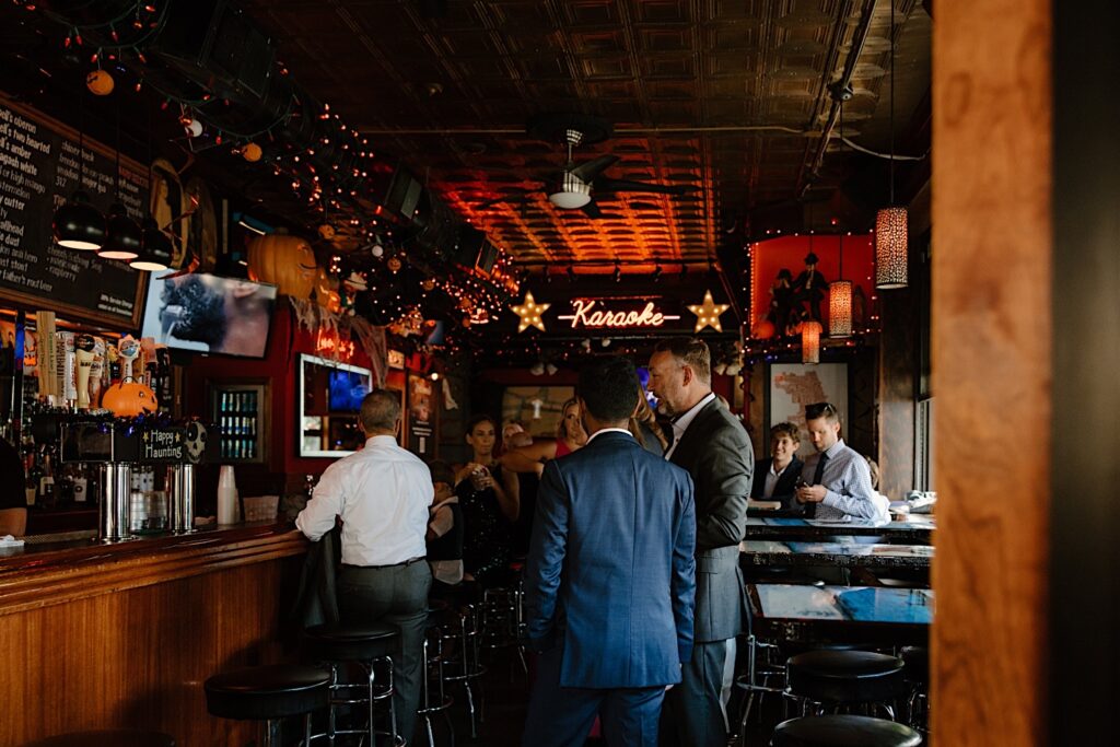 A karaoke dive bar in Chicago during the fall with wedding guests waiting for the arrival of the newlyweds.