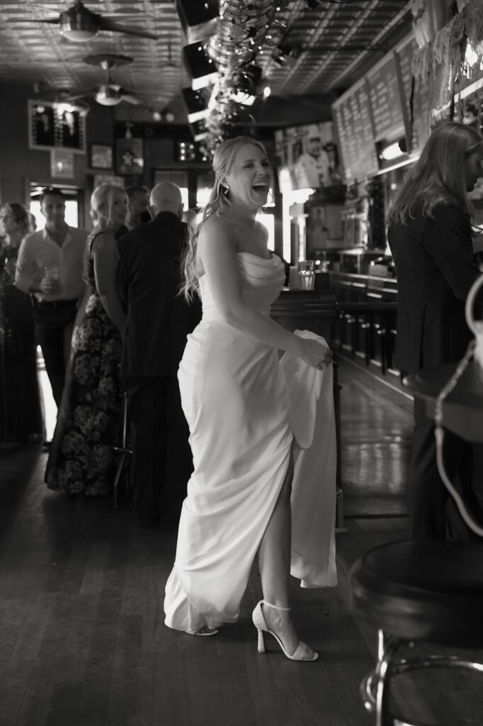 A bride laughs as she approaches the bar with her groom on their wedding day.