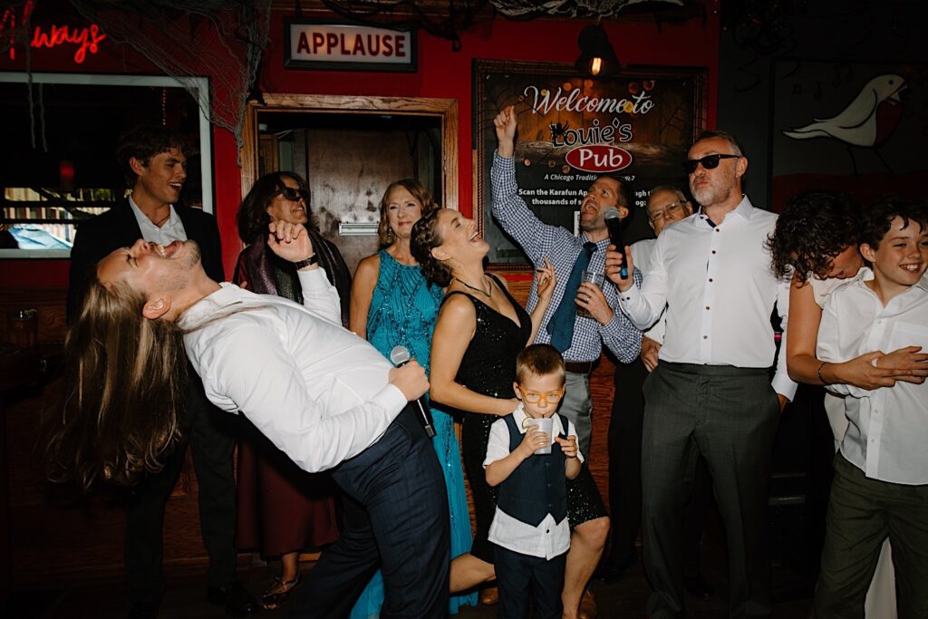 The groom plays air guitar while singing karaoke at Louie's pub in Chicago before his wedding day.  He sings with all of his wedding guests. 