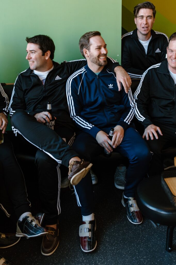 A groom fits in a round of bowling the morning before his wedding with his groomsmen at Avondale Bowl in Chicago.  They're all wearing matching Adidas jump suits and bowling shoes.