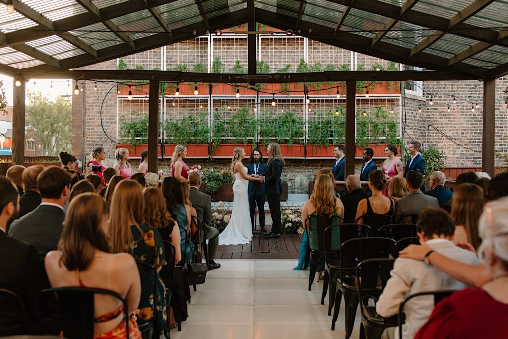 A bride and groom get married in the ceremony space at Homestead on the Roof, a Chicago rooftop wedding venue. 