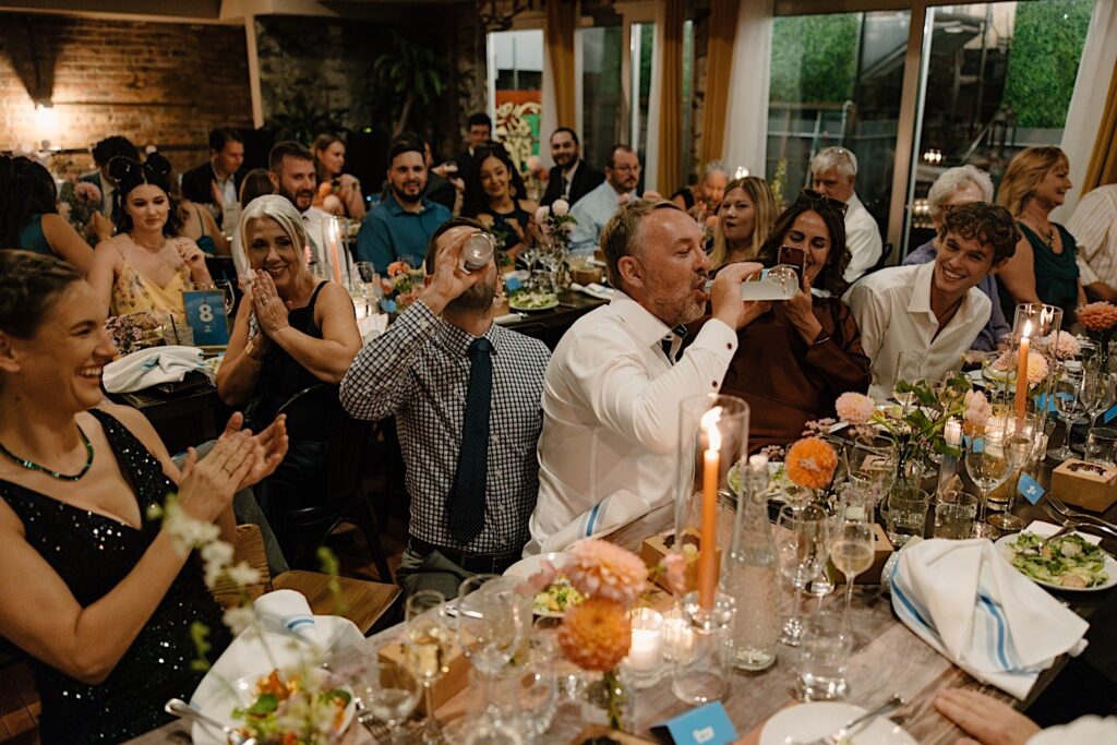 Two guests kneel and drink Smirnoff Ices at a wedding reception in chicago at Homestead on the Roof. 