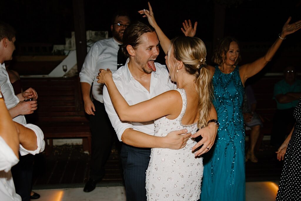 A bride and groom dance together on the dance floor, the bride is wearing her wedding reception dress designed by Clio Peppiatt covered in beads. 