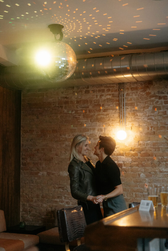 A couple dances under a glowing disco ball. 