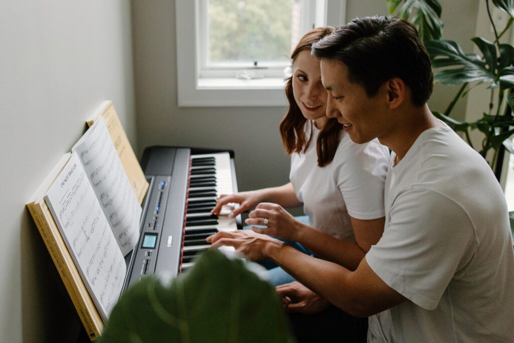 A couple sit together and play piano with one another while in their Chicago apartment for a unique engagement photo